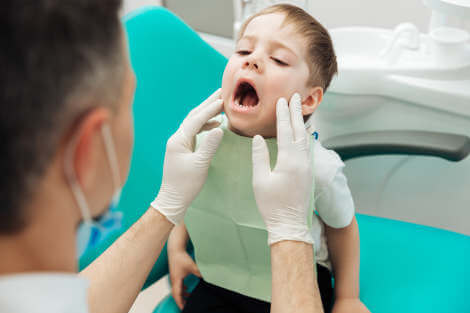 toddler opening his mouth for a dentist exam before installing mouth guards