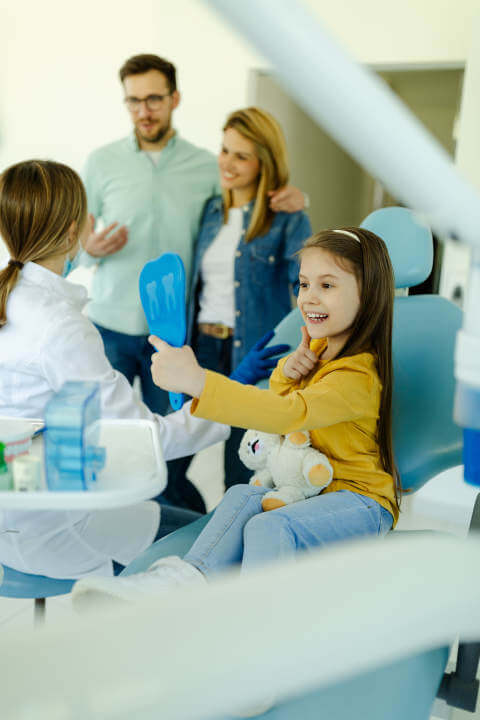 happy toddler sitting at the dentist office after getting her Silver Diamine Fluoride treatment