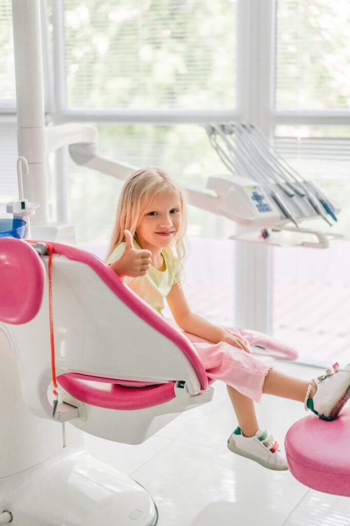 smiling kid showing thumb up while waiting for dentist at dentist office