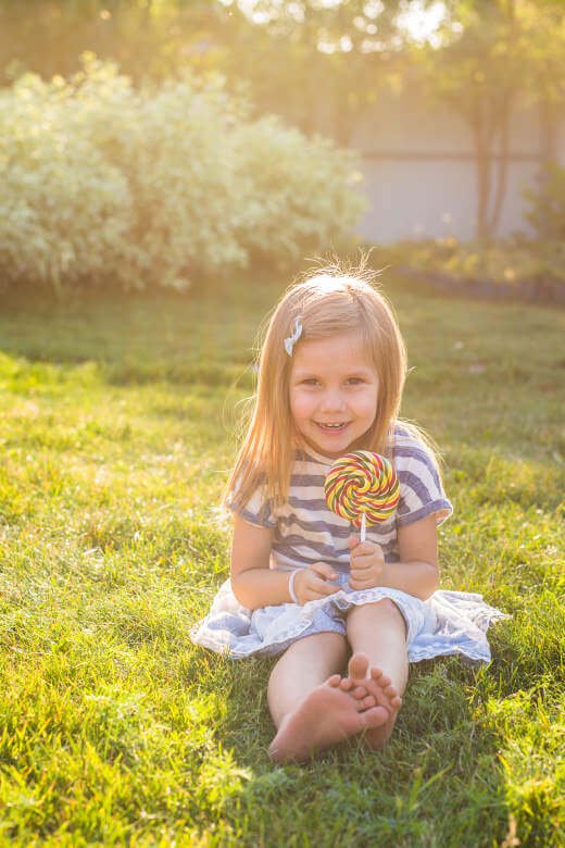 sweet girl licking a lollipop in the yard