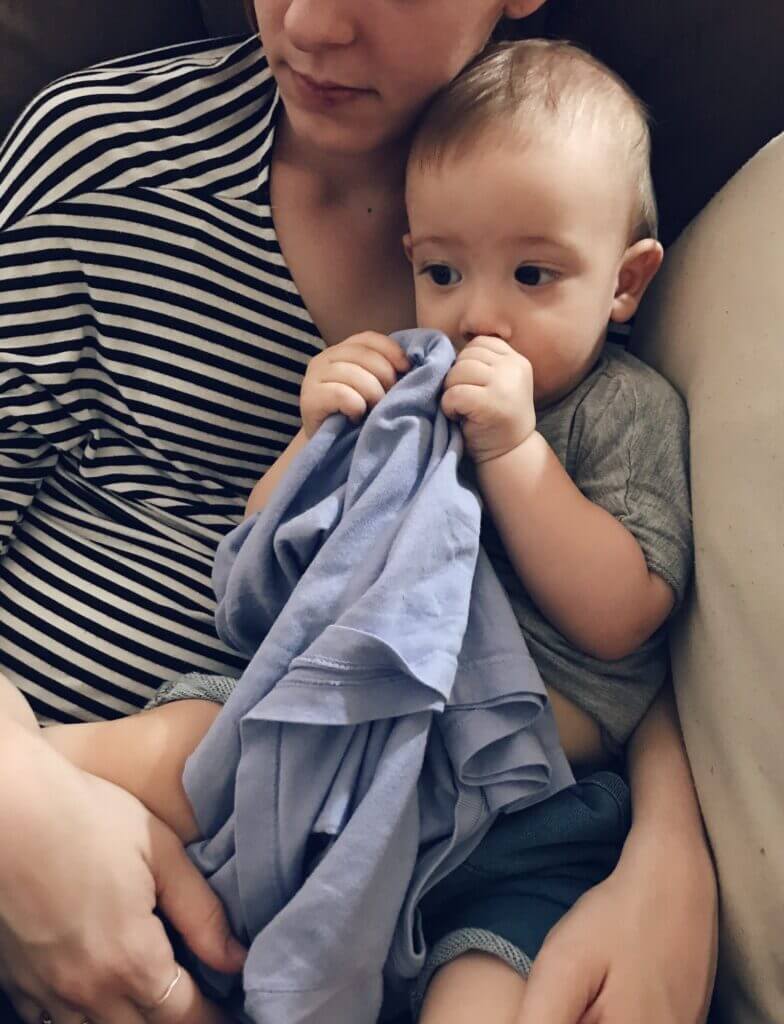 Young toddler is comforted by his mama and sucking his thumb.